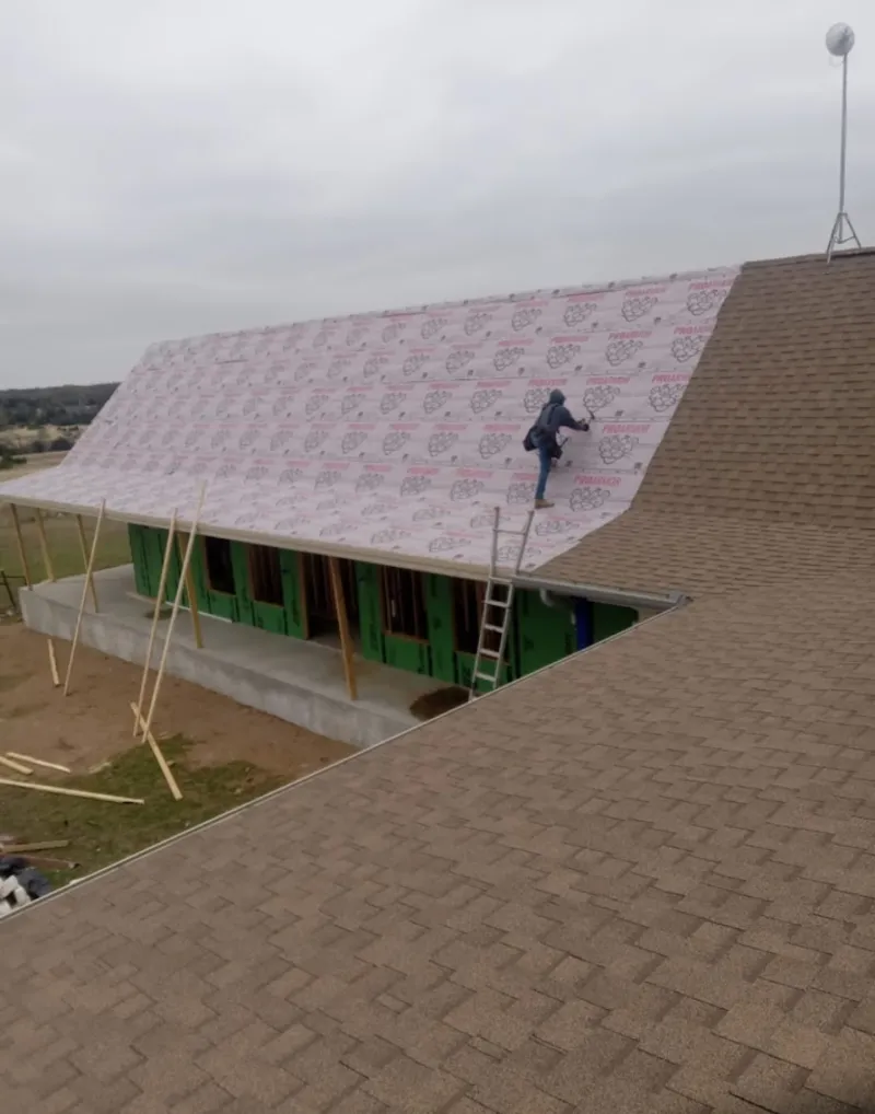 Worker preparing underlayment for a metal roof installation in North East